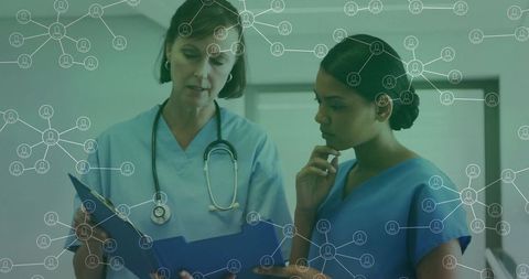 Nurses collaborating in hospital hallway reviewing patient records