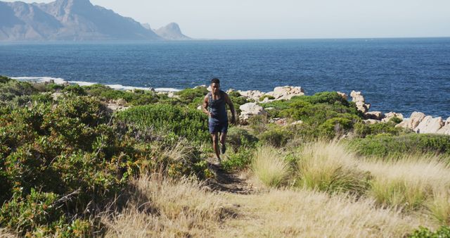 African american man exercising outdoors cross country running in countryside by the coast. fitness training and healthy outdoor lifestyle.