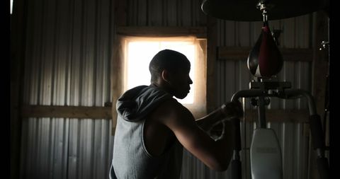 Silhouette of Young Boxer Training with Punching Bag