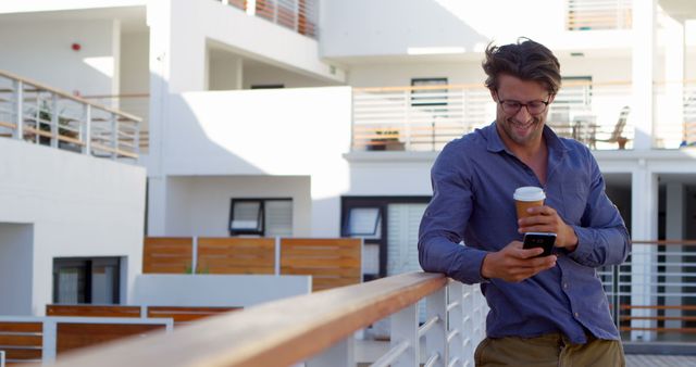 Smiling Man Holding Coffee Cup and Using Smartphone Outdoors - Download Free Stock Images Pikwizard.com