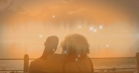 Couple embracing at sunset by the ocean with lens flares