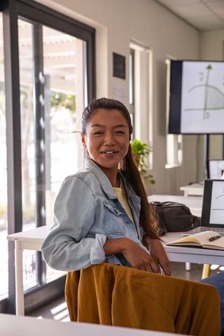 Smiling asian woman studying in modern classroom setting