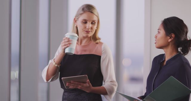 Two Businesswomen Collaborating with Documents and Coffee in Modern Office - Download Free Stock Images Pikwizard.com