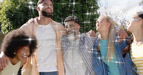 Laughing friends embracing outdoors showing joy and sparkle overlay in sunny park