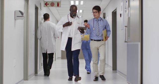 Medical professionals discussing patient care while walking through a hospital corridor. Suitable for topics on healthcare teamwork, collaboration in medical settings, hospital environment, and patient care.