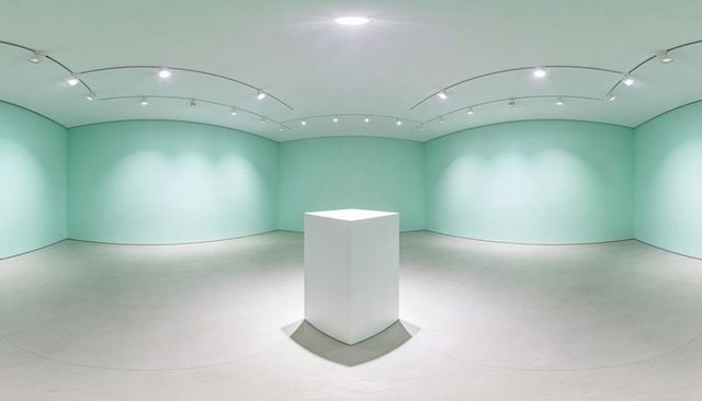 Minimalist mint gallery interior featuring central white pedestal and soft track lighting