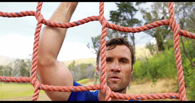 Middle-aged Man Climbing Outdoor Rope Net with Determined Expression - Download Free Stock Images Pikwizard.com