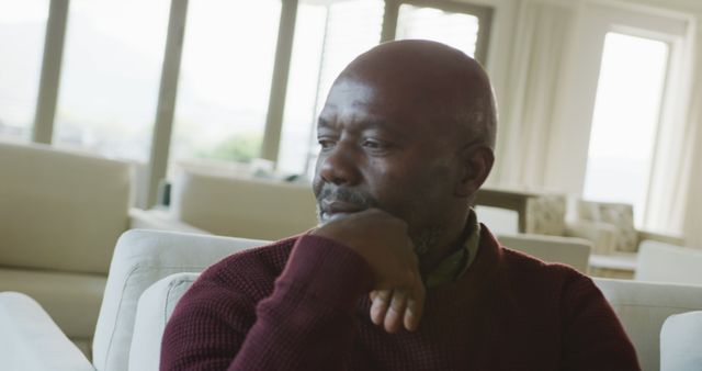 Image of thoughtful senior african american men sitting in living room alone. Retirement lifestyle, spending time alone.