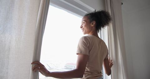 Young African American Woman Opening Curtains for Natural Light