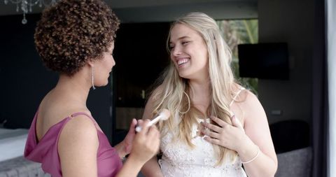 Blonde Bride Talking with Smiling Bridesmaid During Morning Prep