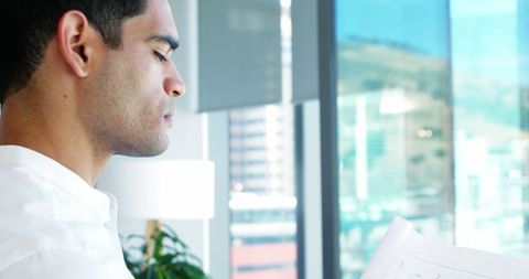 Businessman Analyzing Blueprint During Meeting in Modern Office