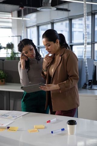 African american and indian colleagues collaborating over tablet in open-plan workspace