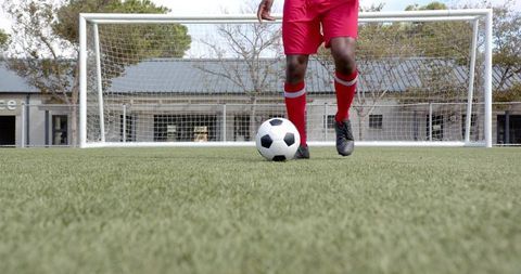Low-Angle Soccer Player Controlling Ball at Goal on Artificial Turf Wearing Red Shorts