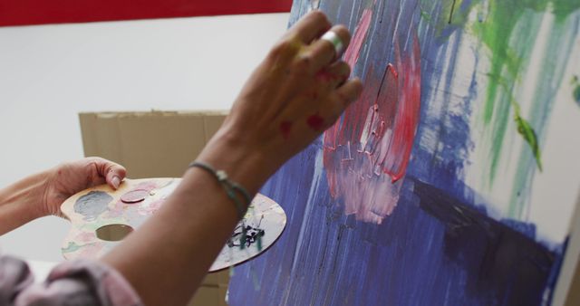 Image of hands of biracial female artist painting in studio. Art, crafts, creativity and creation process concept.