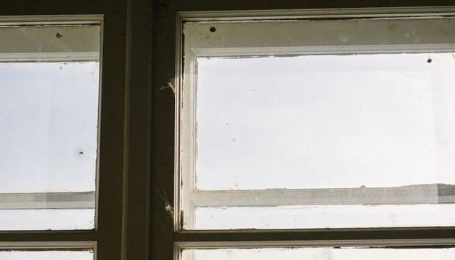 Aged Wooden Window with Cobwebs and Dust Casting Soft Natural Light Through Panes