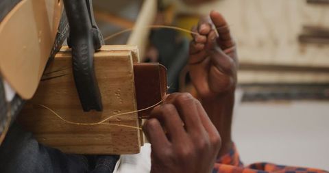Artisan's hands crafting leather wallet with tools in workshop