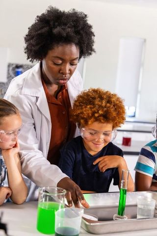African american female teacher guiding kids in hands-on science lab with green chemistry