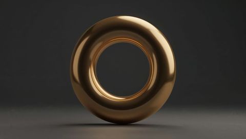 Shiny golden torus sculpture floating on matte gray surface minimal metallic abstract