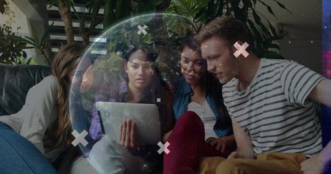 Young adults collaborating around tablet with globe overlay in cozy lounge showing teamwork