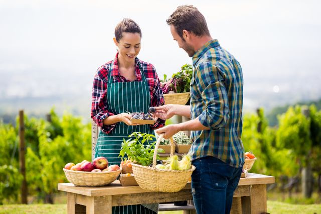 Young woman selling fresh organic vegetables to a man at an outdoor farm stand. The scene is set in a rural countryside with lush greenery in the background. Ideal for use in articles or advertisements about sustainable farming, local agriculture, healthy eating, and community-supported agriculture.