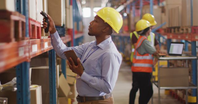 African american male worker with helmet using smartphone in warehouse - Download Free Stock Photos Pikwizard.com