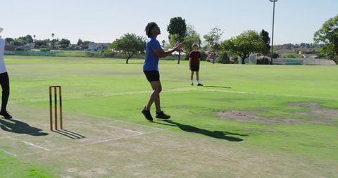 Young player fielding during casual neighborhood cricket match on sunlit park pitch