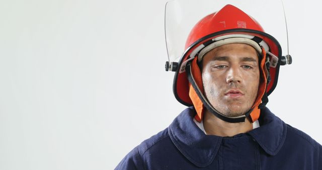 Focused biracial male firefighter wearing hardhat and protecting suit and looking down, copy space. Fire prevention, professionals, safety and expression concept, unaltered.