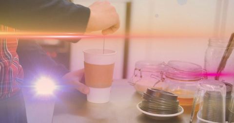 Barista stirring coffee in paper cup on cafe counter