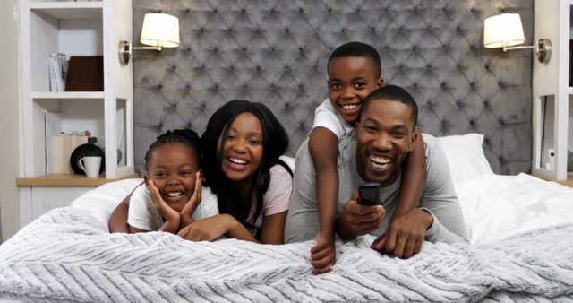 Happy African American Family Watching TV Together in Bed - Download Free Stock Images Pikwizard.com