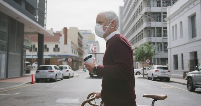 Mature Man Wearing Mask Crossing City Street with Coffee and Bicycle - Download Free Stock Images Pikwizard.com