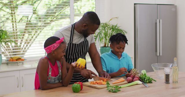 Father and children are preparing a healthy meal together in a bright home kitchen, showcasing family bonding, teamwork, and healthy eating. This image is useful for articles and websites focusing on parenting, healthy lifestyles, family activities, cooking at home, or demonstrating the importance of family meals and spending quality time together.