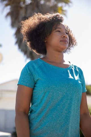 Confident Woman Standing Near Palm Tree on Sunny Day