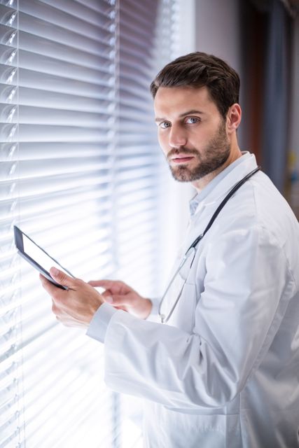 Portrait of male doctor using digital tablet in clinic