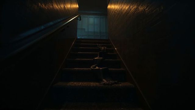 Moody stairwell with person in dark coat and boots