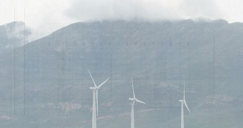 Wind turbines on mountainous landscape with cloudy sky