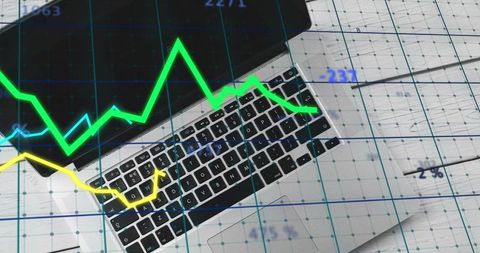 Silver laptop keyboard with overlaid financial line charts for business analytics and trading