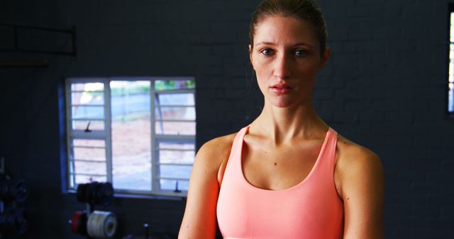 Portrait of woman in sportswear standing in gym with arms crossed