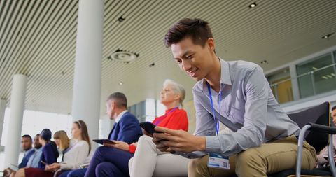 Young Asian Businessman Engaging with Smartphone at Seminar - Download Free Stock Images Pikwizard.com