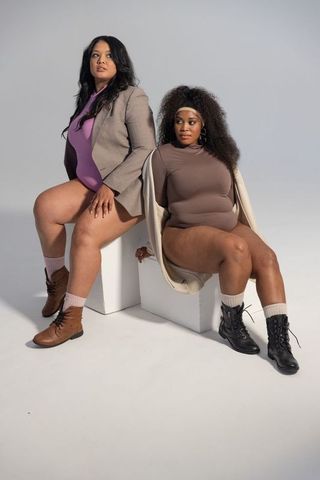 Curvy duo posing in bodysuits and boots, diverse women embracing body confidence