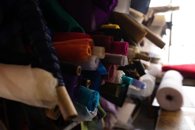Side view of multiple colorful piles of tissues and fabric rolls needed to create hats in the workshop at a hat factory.