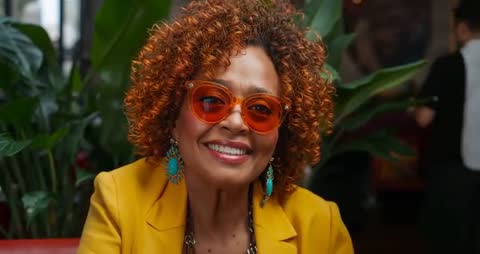 Smiling Woman in Bright Attire Enjoying Café Moment with Sunglasses