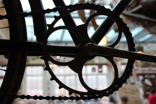 Detailed view of a vintage bicycle sprocket with an industrial and mechanical background. Ideal for use in articles about cycling history, antique machinery, mechanical engineering, or retro aesthetics. Can be used as a visual for cycling enthusiasts, vintage-themed designs, or industrial décor ideas.