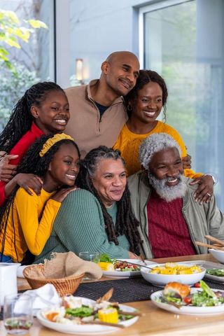 Multigenerational african american family sharing meal smiling together in bright home