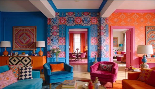 Colorful eclectic living room featuring teal sofa, pink armchairs and patterned wallpaper