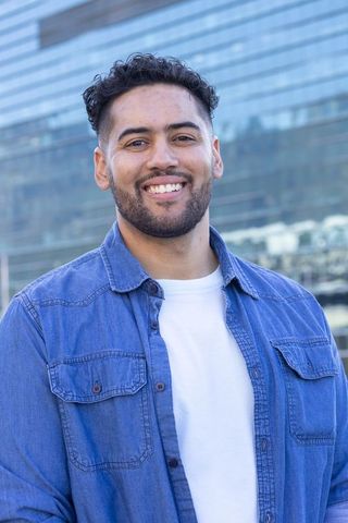 African american man smiling in denim shirt standing by glass facade modern urban portrait