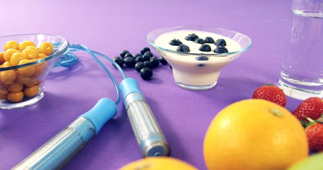 Skipping rope, fresh fruit and yogurt on purple background with copy space. Health, healthy food and diet, fitness and healthy lifestyle concept.