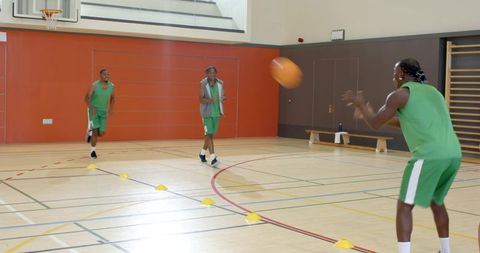 Indoor basketball team practicing cone drills coach calling out passing and footwork