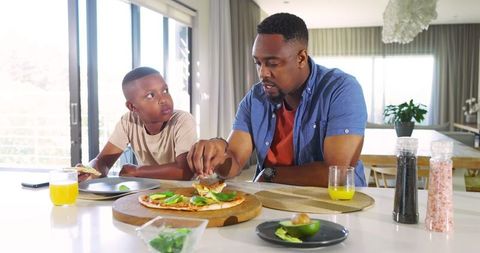 Father and Son Enjoying Pizza Together in Modern Kitchen