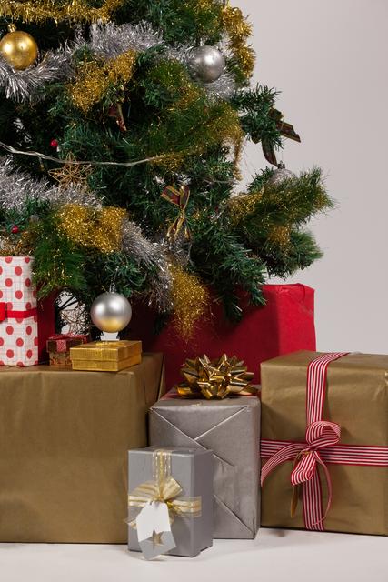 Christmas tree adorned with tinsel and ornaments, surrounded by wrapped gifts in various sizes and colors. Ideal for holiday-themed promotions, festive greeting cards, and seasonal advertisements.