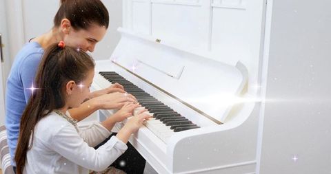 Mother and daughter playing piano together at home